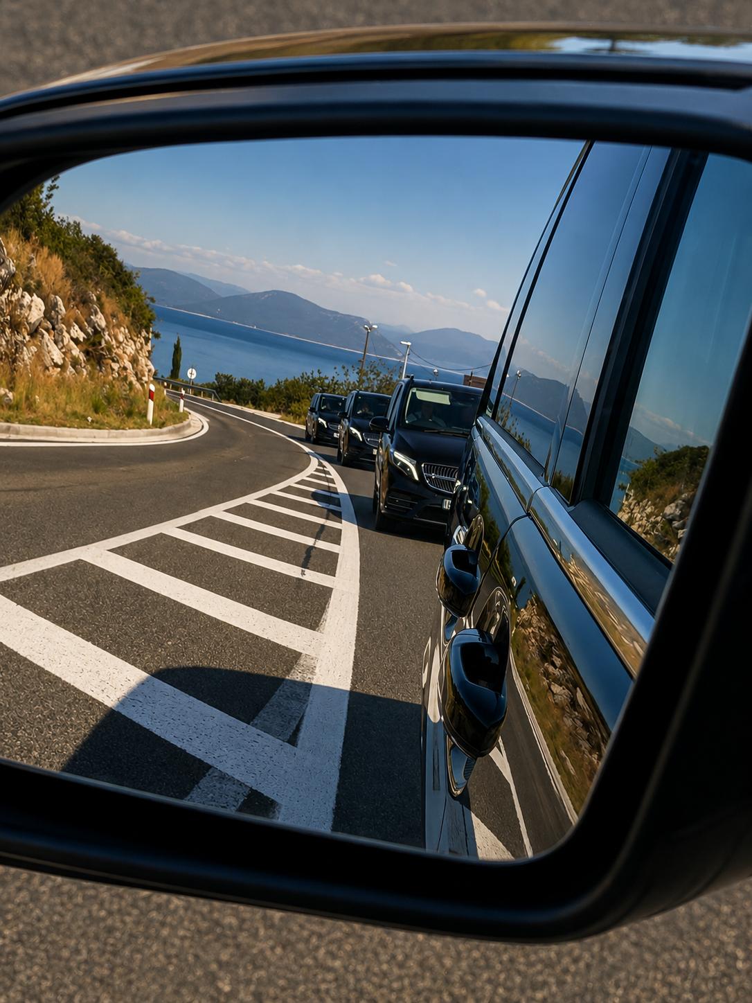 Convoy of black Mercedes-Benz V-Class transfer vehicles on the coastal road below Klis on a private excursion from Split